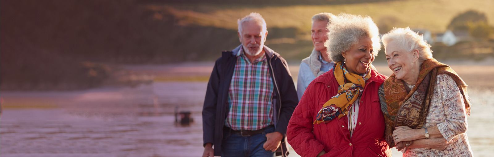 two elderly couples walking along the beach