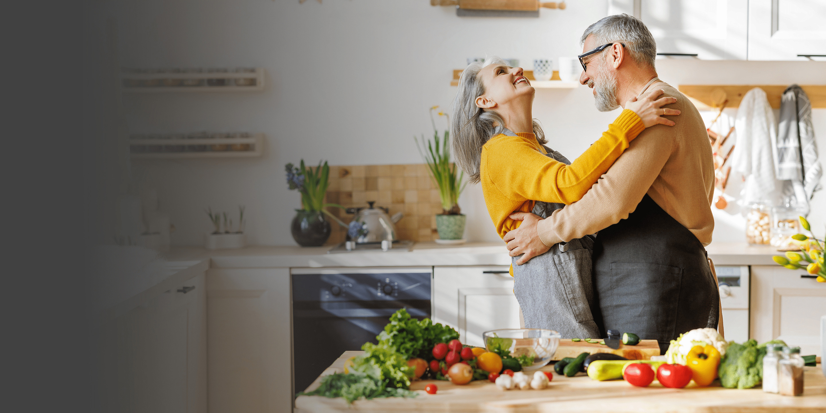 elderly couple dancing together in kitchen and smiling