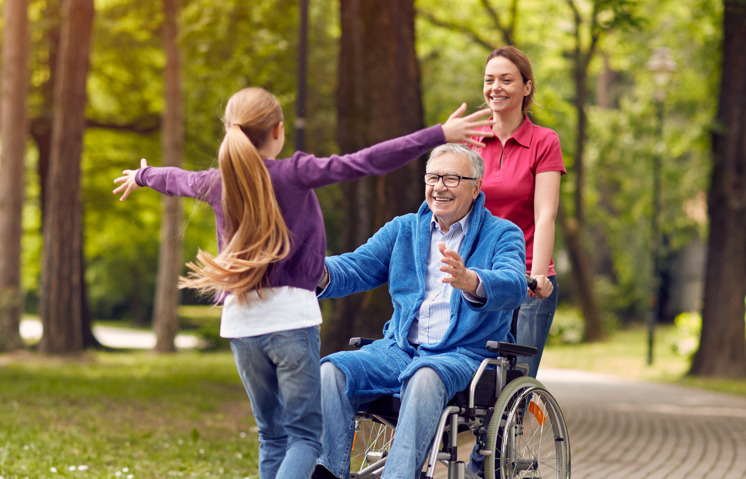 an elderly man in a wheelchair gives grandchild a hug